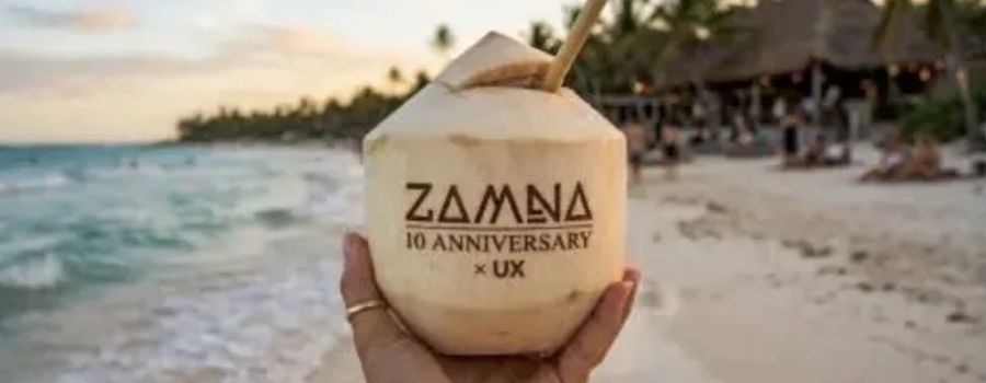 Coco grabado con el logo ZAMNA 10 Anniversary × UX frente al mar